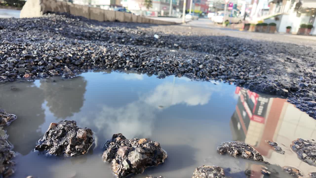 損傷したアスファルト道路に水が溜まった大きなポットホール