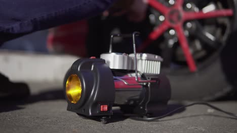 Closeup-portrait-of-a-man-checking-pressure-and-pumping-a-car-tire.