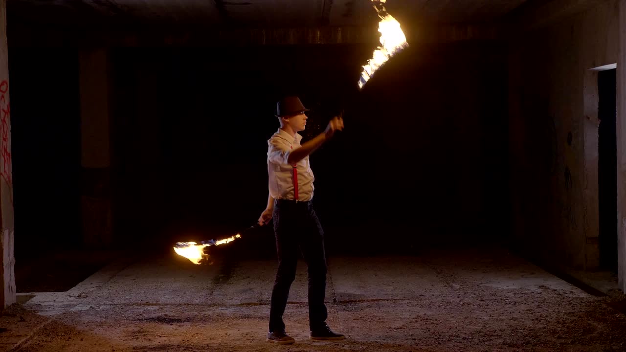 artista masculino realizando un espectáculo de fuego en la oscuridad en cámara lenta.