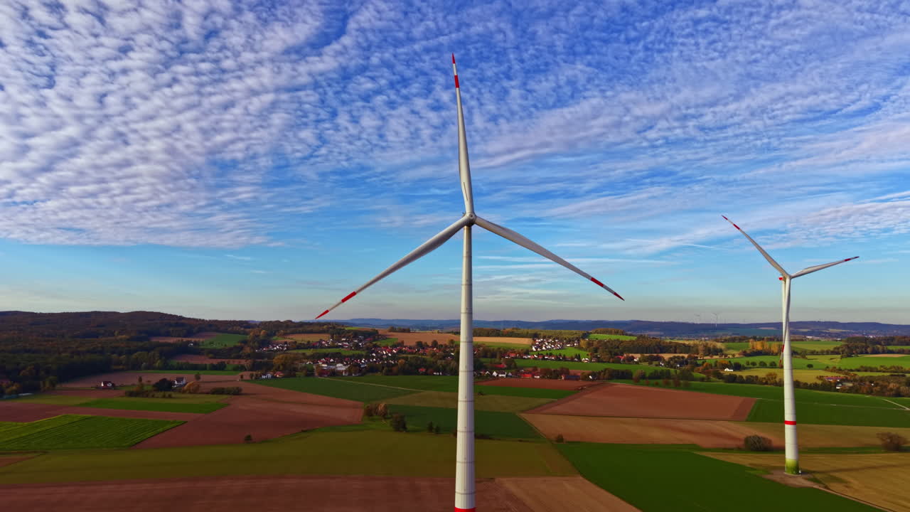 Wind turbines stand tall against a vibrant sky, showcasing renewable energy in a peaceful countryside setting