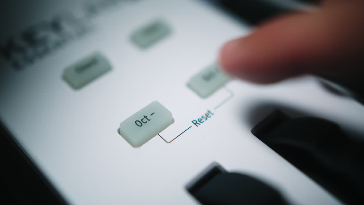 Beautiful slow motion and close-up shot. Musician presses the button to reduce an octave on his Arturia midi keyboard to record a song in his home studio.
