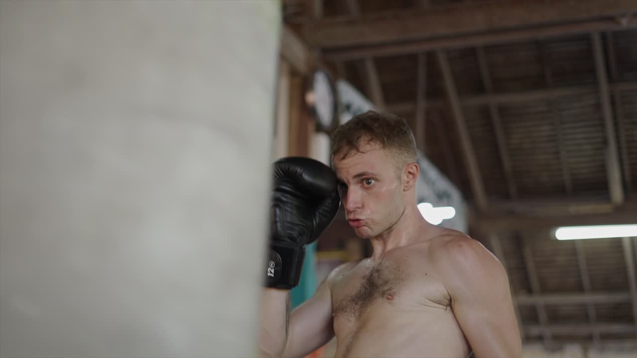 Man training boxing with a punching bag in a gym