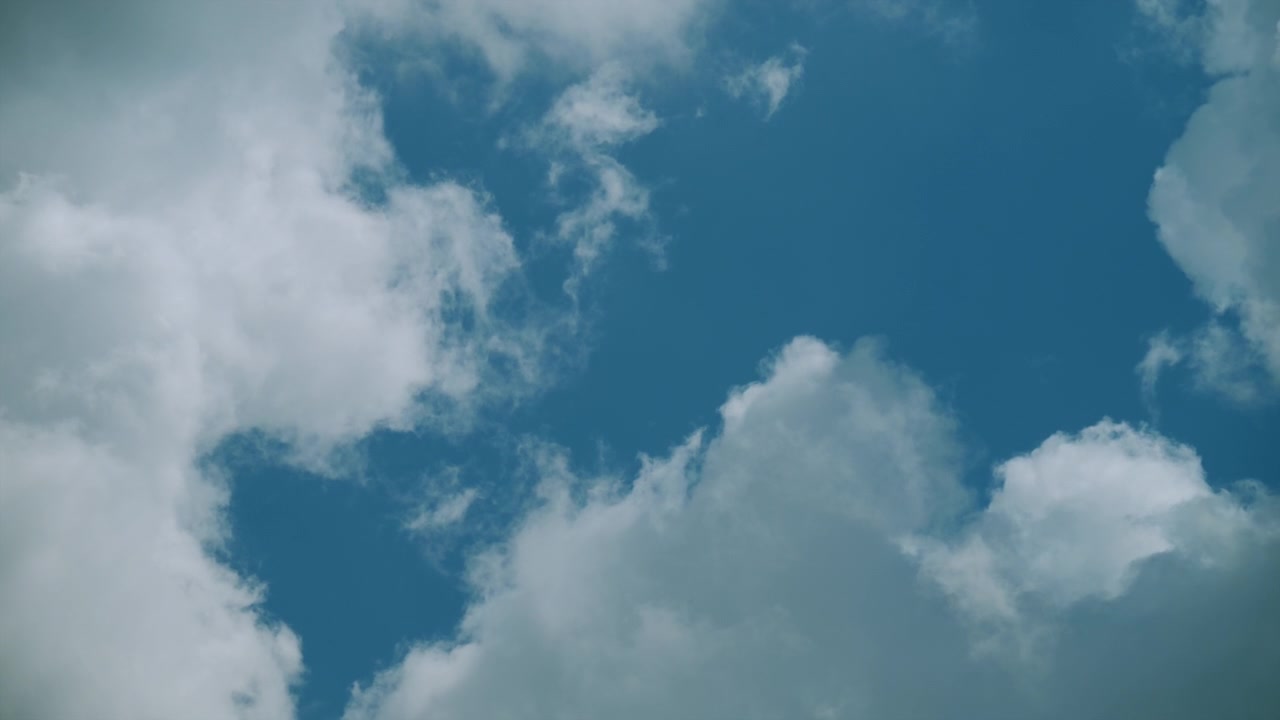 Soft white clouds drift slowly across a bright blue sky, creating a peaceful natural background