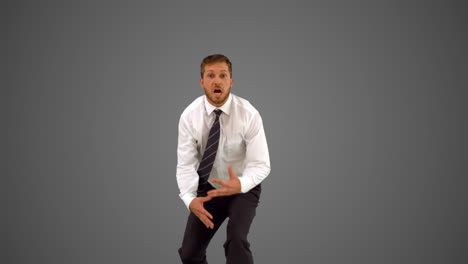 businessman walking towards camera and dancing funnily on grey background