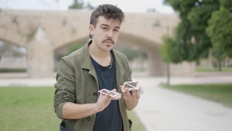 young man performing card tricks in a park