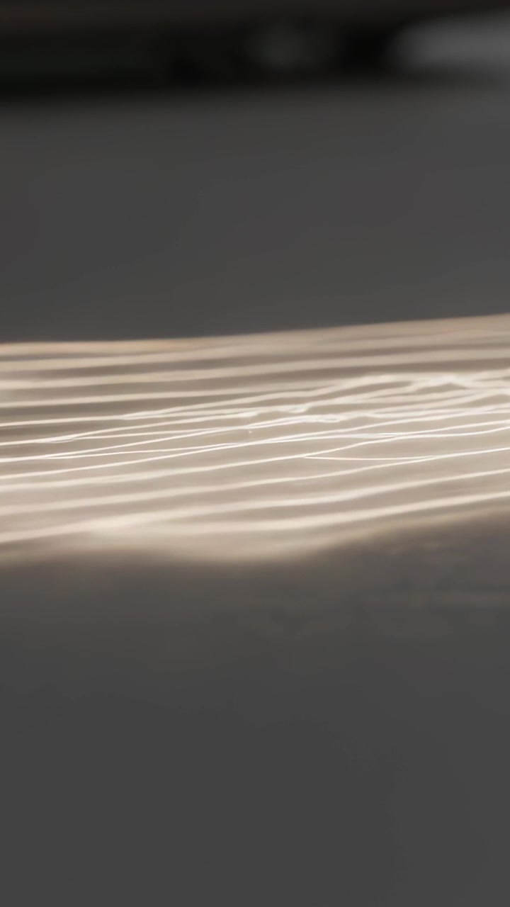 Vertical video: Appearing at left, light dot moving right, making thin streaks on floor, top shadow