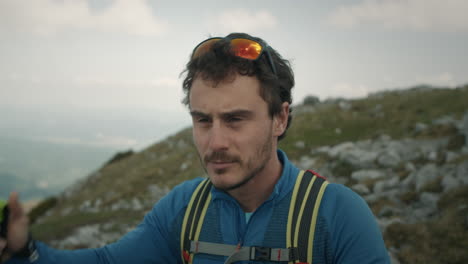 hiker looking into the valley, takes his sunglasses of and puts it on the head, continues to look, takes sunglasses back and continues his journey