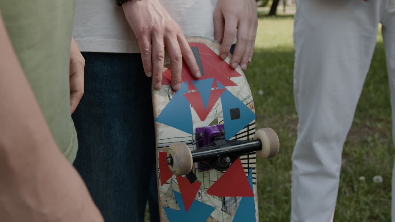 Close-up of a person holding a skateboard with a vibrant design