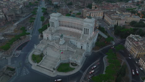 Aerial-slide-and-pan-footage-of-majestic-Vittoriano-monument-at-dusk.-Large-historic-landmark-from-white-marble.-Rome,-Italy