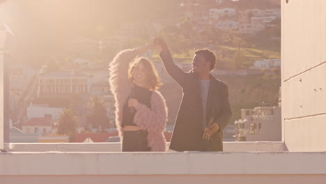 happy young multiracial couple dancing on rooftop at sunset celebrating relationship having fun enjoying playful dance together