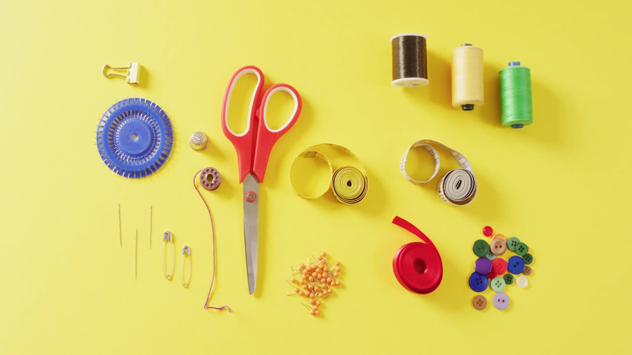 vídeo de cintas métricas, agujas, alfileres, tijeras, botones y hilos de coser sobre fondo amarillo
