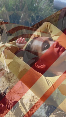 animation of american flag over biracial woman lying in mountains