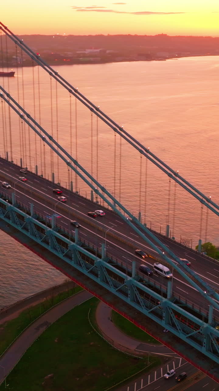 Amazing sunset coloring everything in pink. Whitestone bridge with fast moving cars over East river. Vertical video