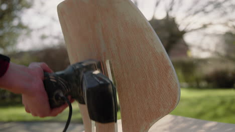 handyman using polishing machine refurbishing an old vintage design chair in the garden on a sunny day 4k