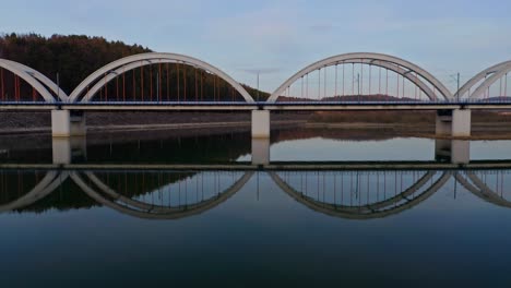 Puente-Ferroviario-De-Arco-Atado-Con-Un-Reflejo-Perfecto-En-El-Río-Skawa-En-Wadowice,-Voivodato-De-Menor-Polonia,-Polonia