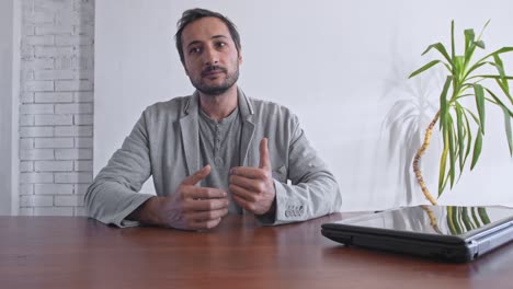 blogger at work with a laptop on the table against the background of a white wall and a green plant