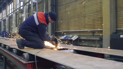 metal worker grinding metal sheet in factory