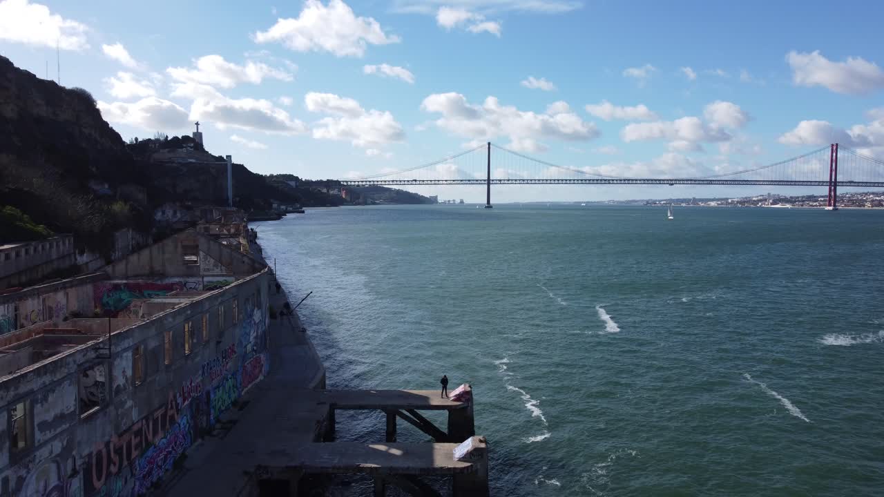 Dronie shot from a pier revealing an amazing vista with the 24th of April bridge in Lisbon in the Background