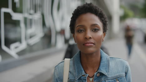 portrait of young african american woman commuter looking serious at camera in urban city street background independent black female wearing denim jacket