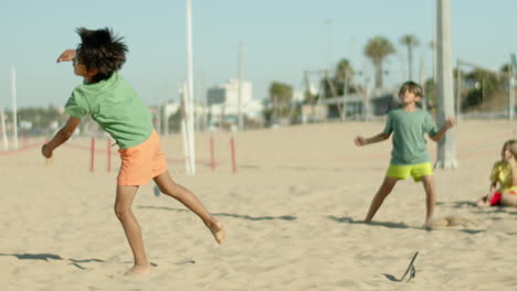 slow motion of happy kids perfecting football tricks on seashore