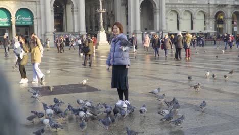 a lady feeding to pigeons in front of duomo di milano