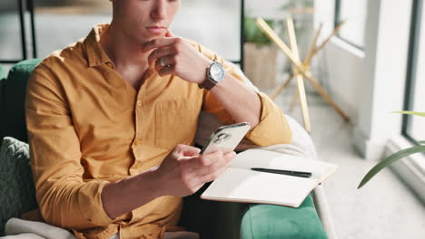 man using a phone while sitting on an armchair