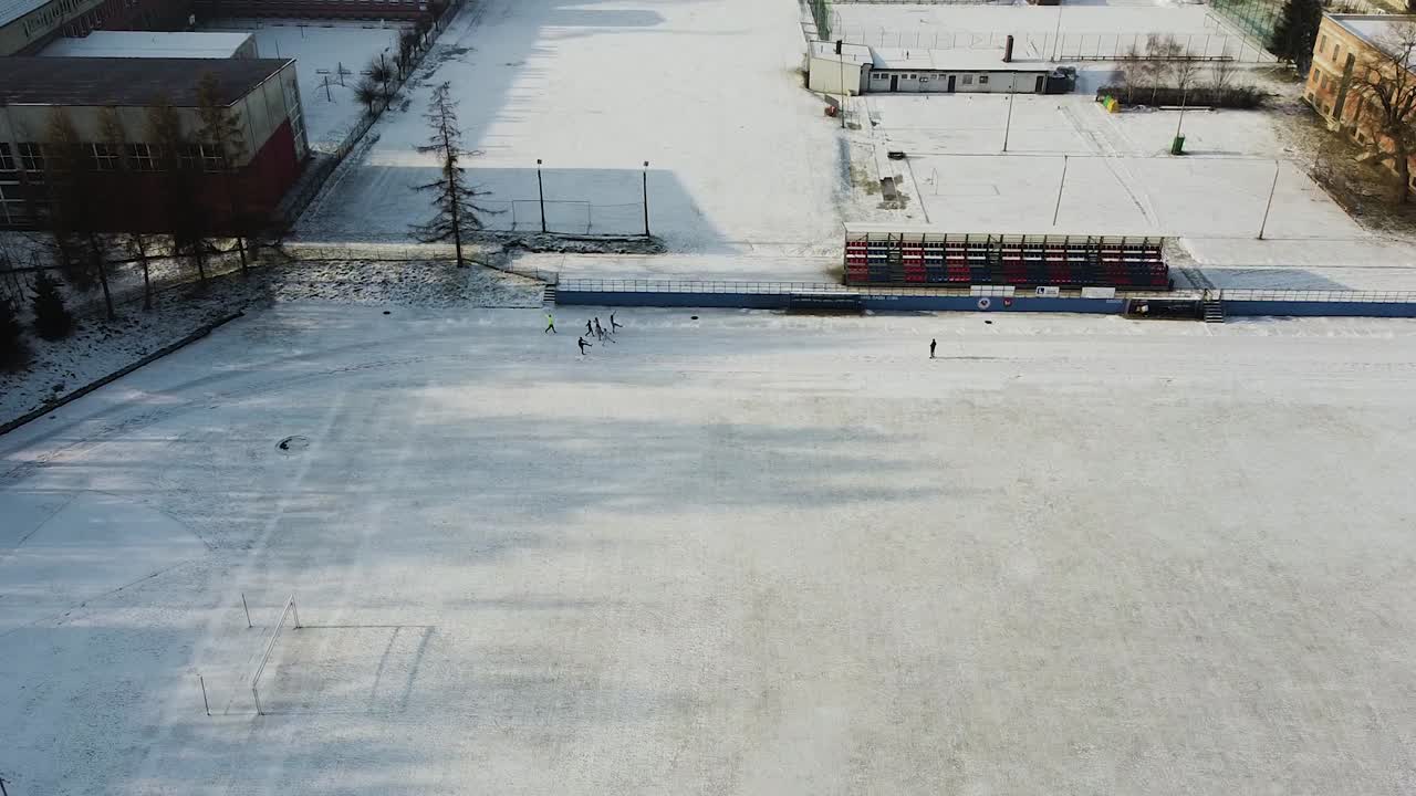 grupo de corredores calentándose en un campo de deportes nevado, invierno calentando drones