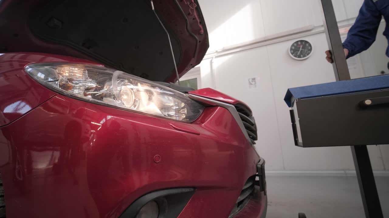 노동자는 자동차 조명 시스템의 헤드라이트를 확인하고 조정합니다.