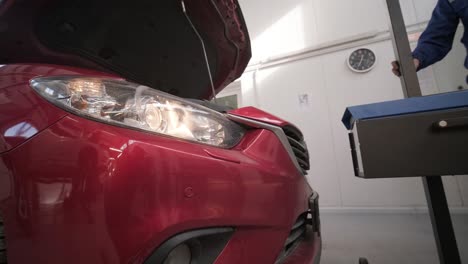 trabajador comprueba y ajusta los faros del sistema de iluminación de un automóvil. servicio de reparación de automóviles.