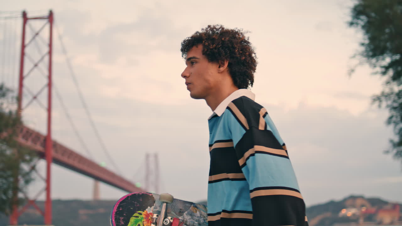 estudiante involucrado cruzando la calle al atardecer. patinador escondiendo teléfono inteligente verticalmente