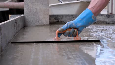 Persona-Con-Guantes-Azules-Pavimentando-El-Piso-De-Cemento