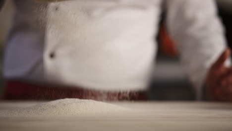 Professional-chef-cooking-flour-on-cafe-kitchen.-Man-baker-sifting-using-sieve.