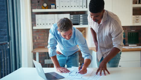 two male architects with laptop meeting and discussing building plans in modern office