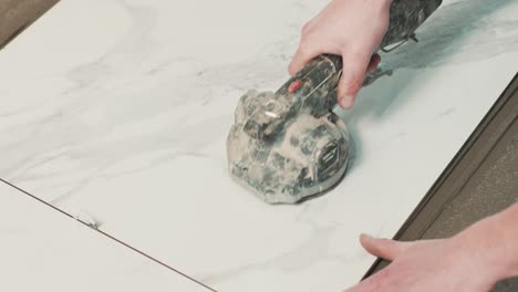 construction worker using a tile vibrator machine to install ground tiles