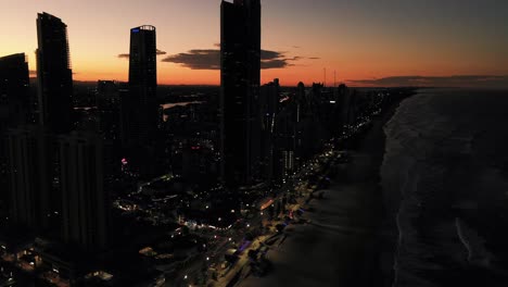 Late-sunset-at-Surfers-Paradise,-Golden-skies-behing-highrise-apartments-,drone