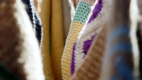 close-up of colorful crocheted and knitted blankets hanging on a line