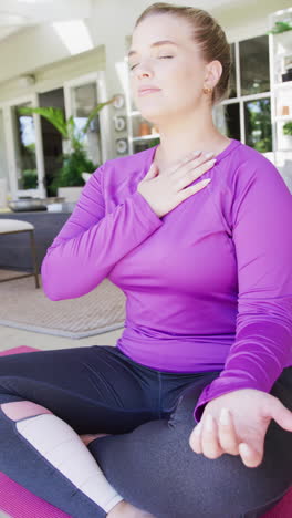 vertical video of happy caucasian plus size woman practicing yoga in slow motion