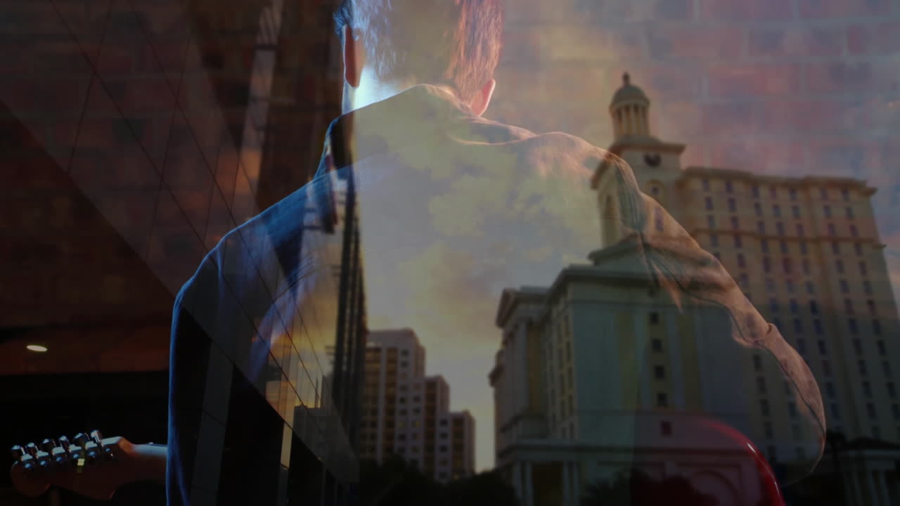 male musician playing guitar indoors, blending skyline graphics over sunset light for music theme