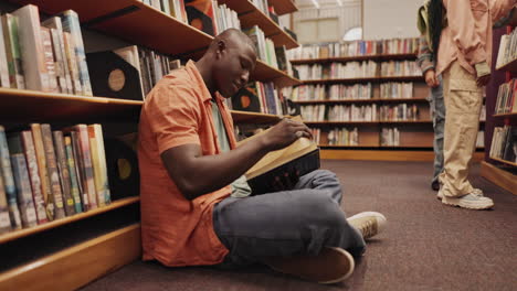 un hombre leyendo un libro en una biblioteca