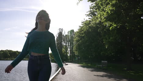 Beautiful-Italian-girl-walking-peacefully-in-a-tranquil-park-wearing-a-shimmery-sweater-in-London,-United-Kingdom