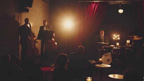 a saxophonist plays under warm spotlight against red curtains. the video captures a close-up angle