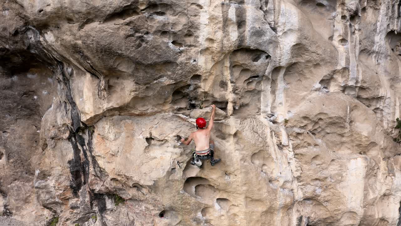 Rock climber ascending a karst mountain rock face in China, aerial tracking view