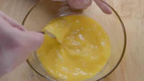 slow motion shot of whisking eggs with a fork in the kitchen