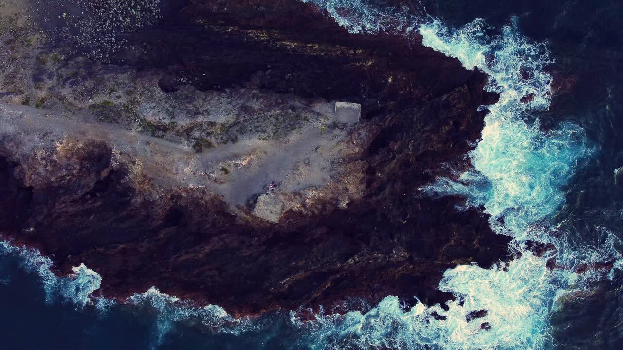 tierra rocosa rodeada de agua azul del océano en los cristianos, tenerife