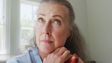 Senior-caucasian-woman-wearing-blue-shirt-and-sitting-with-cane-in-living-room