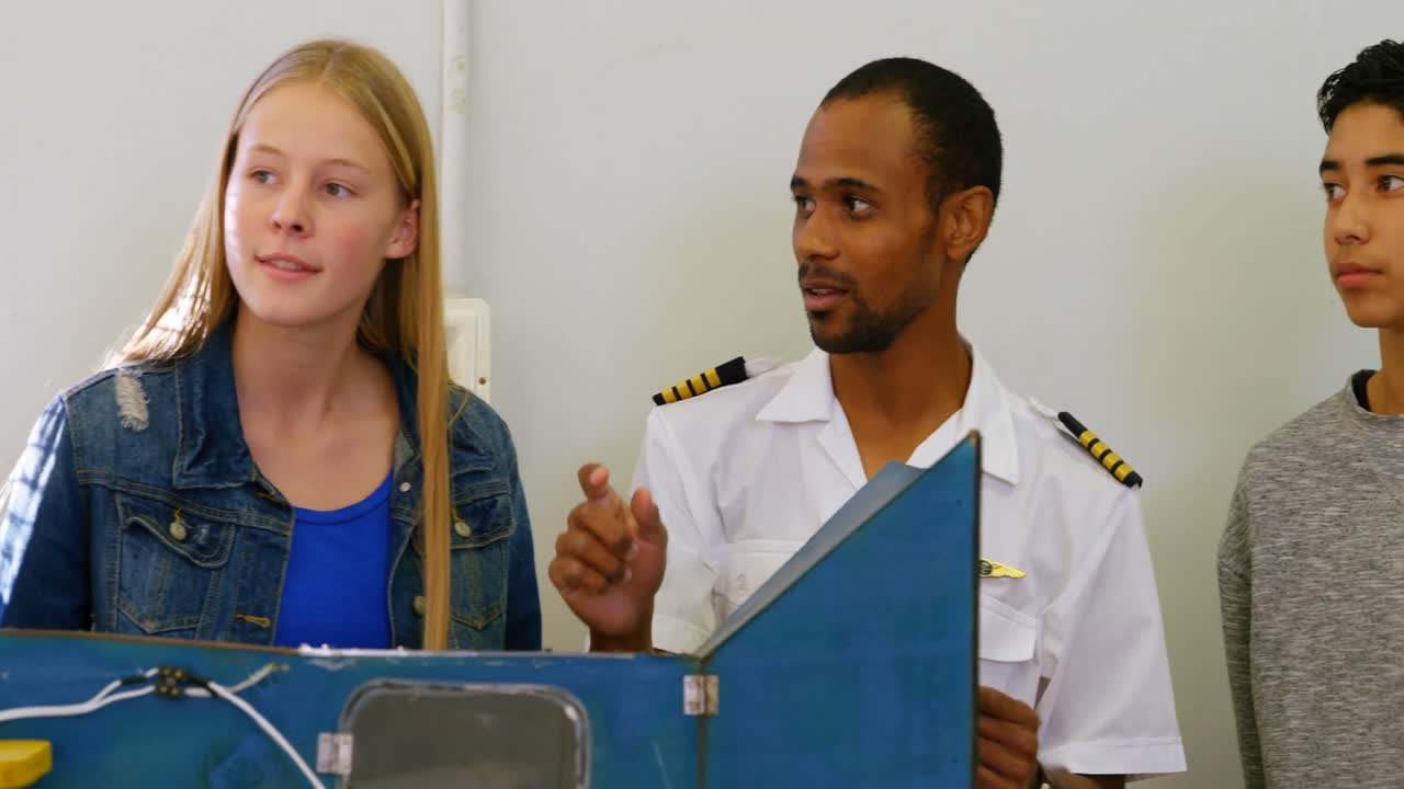 남자 조종사가 아이들에게 기계에 대해 설명하고 있습니다. 4k