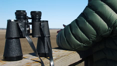 person sets binoculars on wooden guard rail