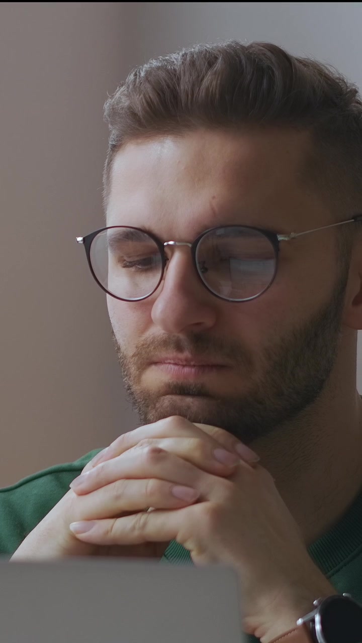Giovane uomo pensieroso con gli occhiali che si concentra mentre lavora