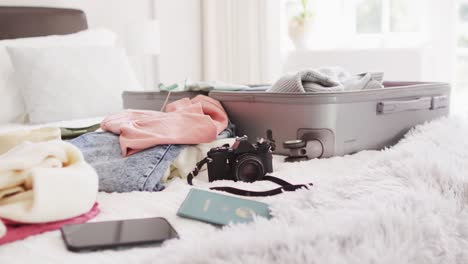 Video-of-passport,-smartphone,-camera,-clothes-and-suitcase-on-bed