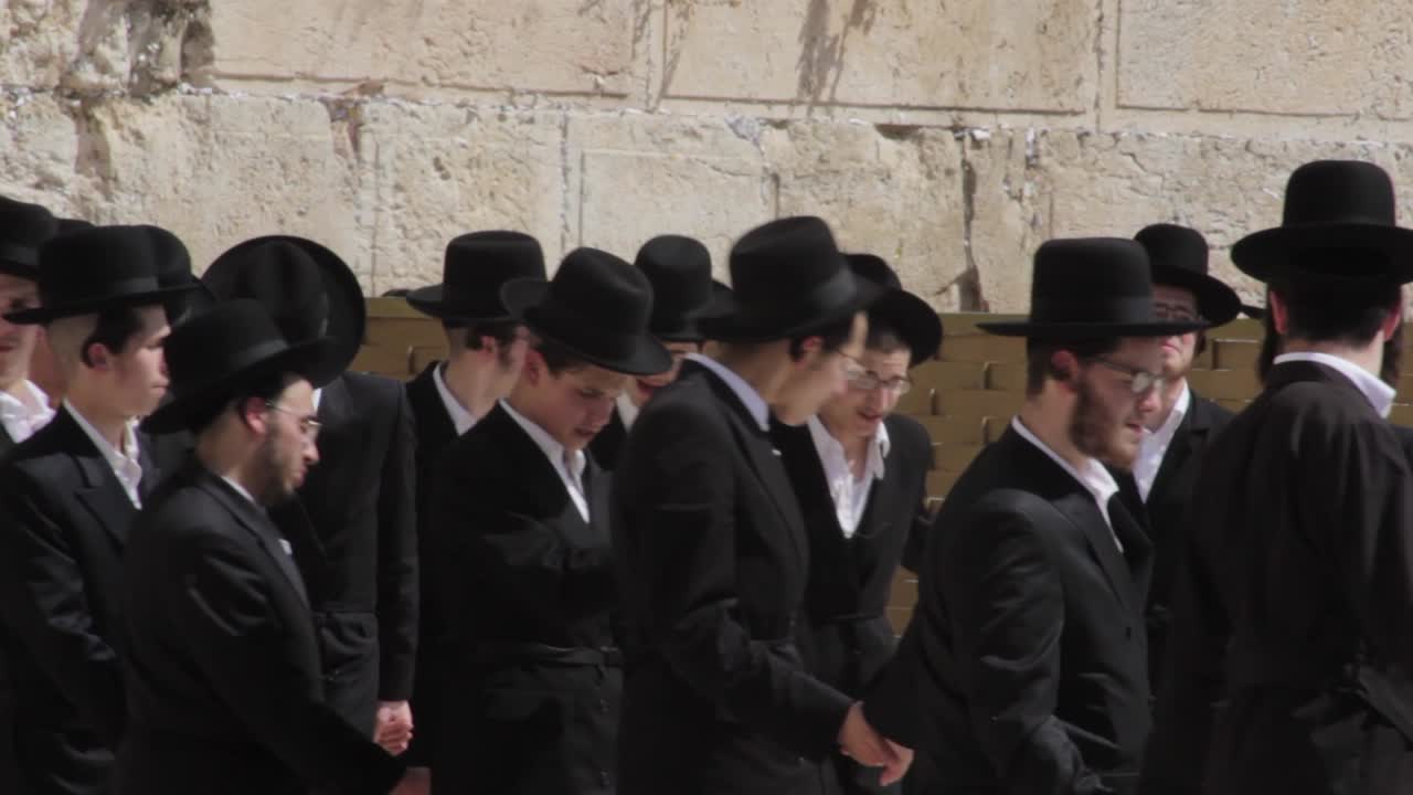 Orthodox Jewish men and boys dance at the Western Wall in Jerusalem beneath the temple mount